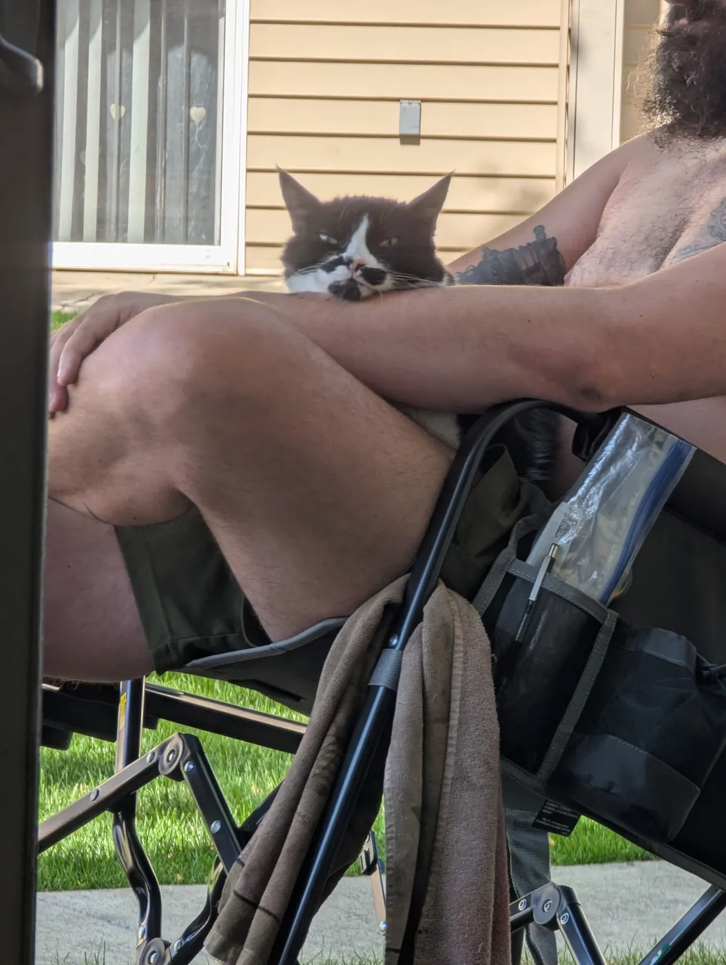 Rorschach peering over Tyler's shoulder as he sits in a camp chair on the patio
